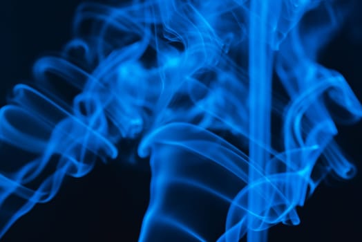 Blue abstract shaped smoke against black background. Abstract background. Selective focus