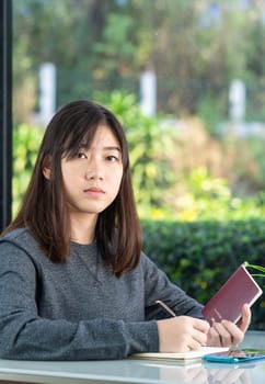 Young woman sitting sholding passport and credit card in home office