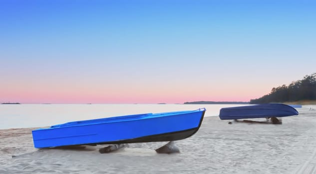 Fishing boats on an empty sandy beach against the pink sunset in a cloudless sky. Coast of Lake Onega in the White Nights season, Republic of Karelia, Russia. Selective focus, space for copy.