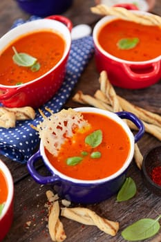 Homemade tomato soup in little pots with parmesan crackers