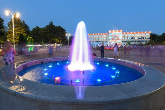 Anapa, Russia - July 17, 2020: A small fountain and tourists taking pictures of it in front of the Sovetov Square in Anapa