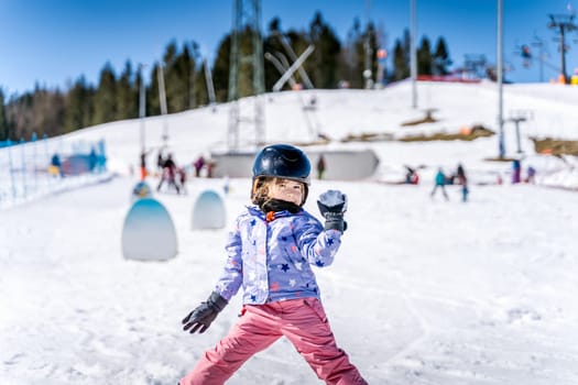Young happy skier girl throwing snowballs in snowball fight. Young skier having fun on ski slope, Bialka Tatrzanska, Tatry, Poland