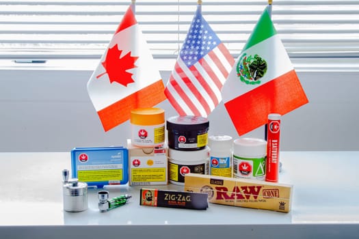 Calgary, Alberta, Canada. Sep 18, 2020. Canadian legal cannabis popular brands of marijuana weed plastic containers with USA, Mexico and Canada flag.