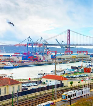 Seagulls over Lisbon commercial port, ships containers and freight cranes, skyline with 25th April Bridge and Tagus river, Portugal