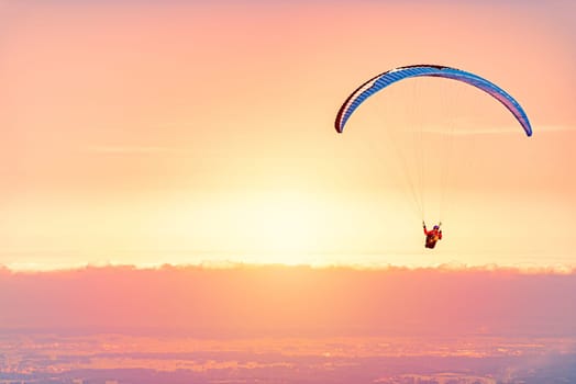 Paraglider at sunset in Germany, Bavaria, Europe. Orange sky with clouds in background.