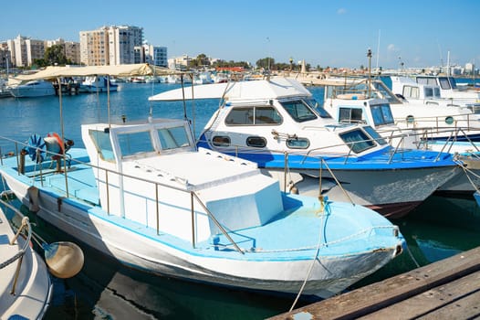 Motorboats in marina of Larnaca in bright sunshine, city embankment in background, Cyprus