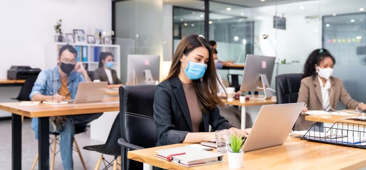 Panoramic group of business worker team wear protective face mask in new normal office with social distance practice with hand sanitiser alcohol gel on table prevent coronavirus COVID-19 spreading