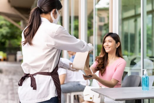 Asian Young adult in car holding disposable bag for take out food from drive thru service restaurant. Drive thru is new normal and popular service after coronavirus covid-19 pandemic.