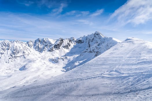 People skiing and snowboarding from Kasprowy Wierch, winter holidays. Amazing mountain range with snow capped mountain peaks in Tatra Mountains Poland