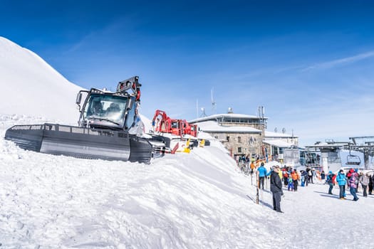 Zakopane, Poland March 2019 Tourists sightseeing the tope of Kasprowy Wierch with multiple snow groomers parked on site and ski lifts in background