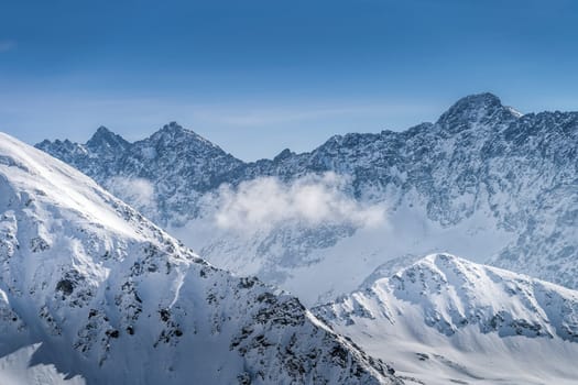 View from Kasprowy Wierch at rocky mountain peak at winter. Amazing mountain range with snow capped mountain peaks in Tatra Mountains, Poland