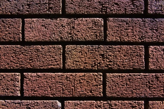 2 - Abstract texture close up of a red brick wall shadows and bright highlights make contrasted image. Fine grain and structure visible. Horizontal.