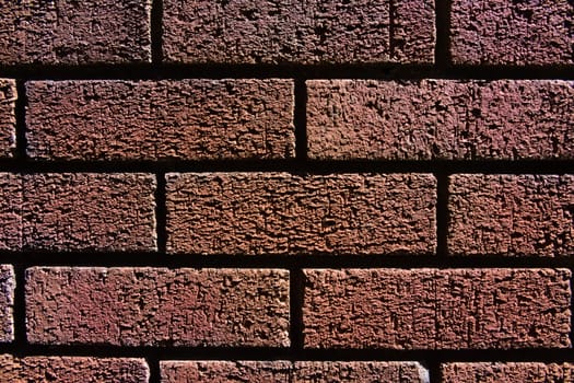 1 - Horizontal red brick wall background texture. Monochromatic appearance and dark shadows between the bricks.