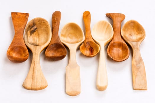 Different unique wooden spoons on white background, kitchen equipment, wood carving concept.