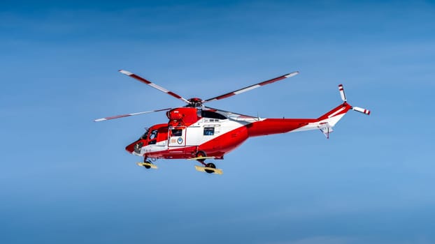 Red and White helicopter, rescue team or crew flying over Kasprowy Wierch and Swinica in High Tatra Mountains, providing rescue service, Poland