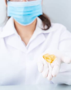 Close up Scientist hands putting in nitrile latex gloves holding Omega 3 capsule in labcoat wearing nitrile gloves, doing experiments in lab