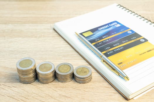 Top view coins with note pad and credit card on wood table using as financial concept