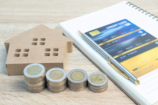 House model and coins with credit card on wood table using as property real estate and financial concept