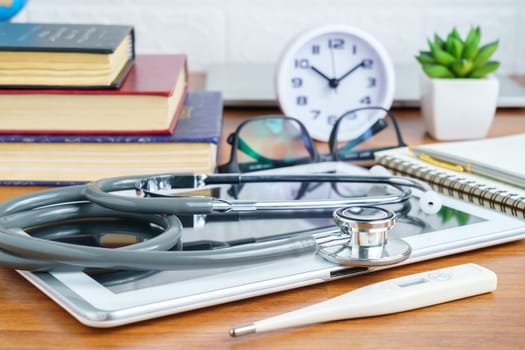 Medical stethoscope for doctor checkup with tablet computer on doctor table as medical concept