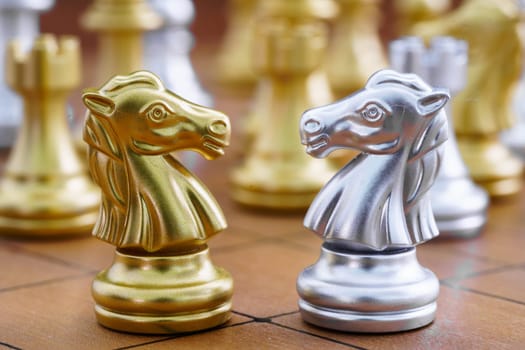Gold and siver horse of the chess in the game on chessboard