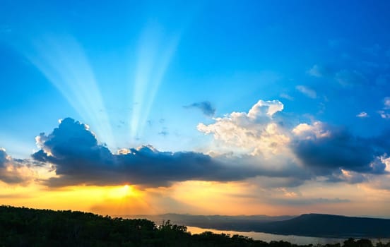 Sunset with ray light on clouds in a blue and orange sky in twilight time