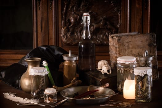 eerie witches' kitchen with lot of ingredients for a potion and ancient gruesome jars dark with only candlelight for Halloween