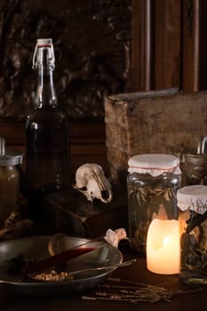 eerie witches' kitchen with lot of ingredients for a potion and ancient gruesome jars dark with only candlelight for Halloween