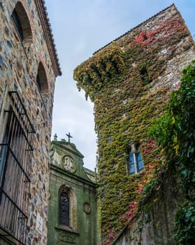 Sande Tower, Medieval old palace house hidden in green and red ivy, Caceres, Extremadura, Spain