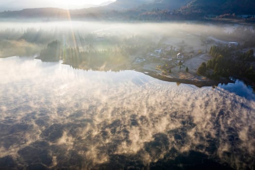 Magic foggy sunrise over Colibita lake at autumn, Romania.