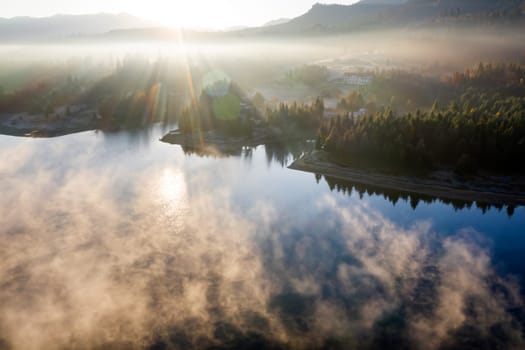 Magic foggy sunrise over Colibita lake at autumn, Romania.
