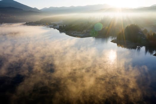 Magic foggy sunrise over Colibita lake at autumn, Romania.