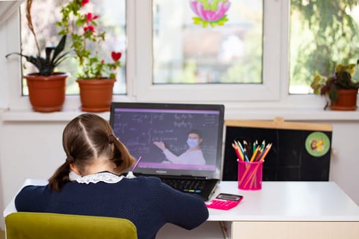 Distance learning-online education. School girl watching online education classes and doing school homework. COVID-19 pandemic forces children online learning.