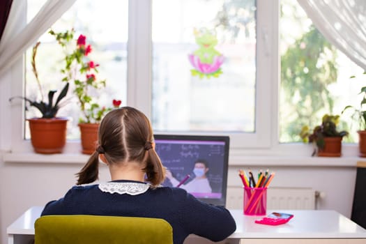 Distance learning-online education. School girl watching online education classes and doing school homework. COVID-19 pandemic forces children online learning.