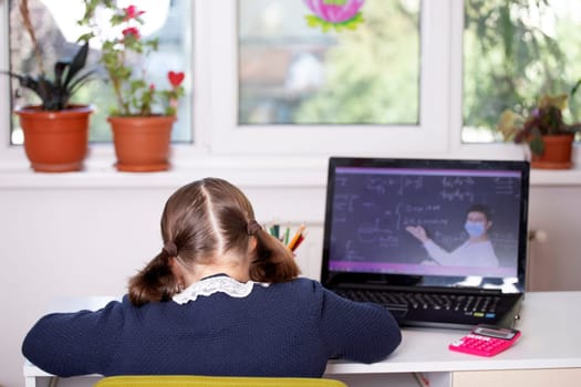 Distance learning-online education. School girl watching online education classes and doing school homework. COVID-19 pandemic forces children online learning.