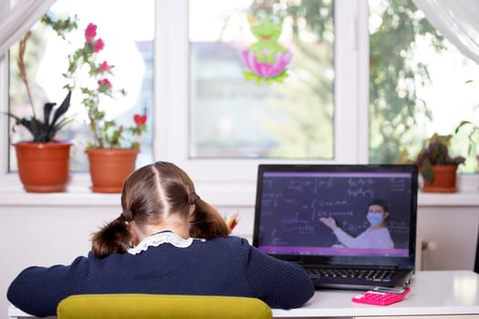 Distance learning-online education. School girl watching online education classes and doing school homework. COVID-19 pandemic forces children online learning.