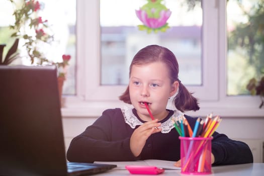 Distance learning-online education. School girl watching online education classes and doing school homework. COVID-19 pandemic forces children online learning.