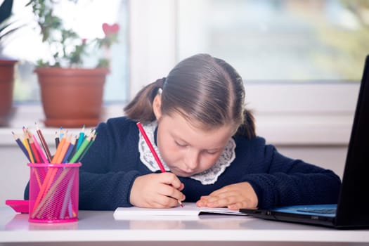 Distance learning-online education. School girl watching online education classes and doing school homework. COVID-19 pandemic forces children online learning.
