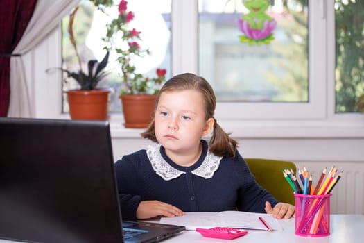 Distance learning-online education. School girl watching online education classes and doing school homework. COVID-19 pandemic forces children online learning.
