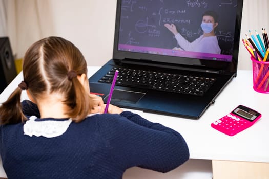 Distance learning-online education. School girl watching online education classes and doing school homework. COVID-19 pandemic forces children online learning.