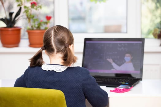 Distance learning-online education. School girl watching online education classes and doing school homework. COVID-19 pandemic forces children online learning.