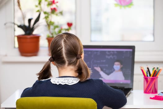 Distance learning-online education. School girl watching online education classes and doing school homework. COVID-19 pandemic forces children online learning.