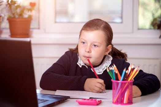 Distance learning-online education. School girl watching online education classes and doing school homework. COVID-19 pandemic forces children online learning.