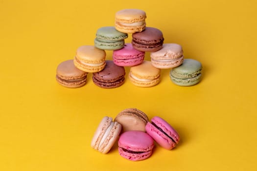 Pastries, desserts and sweets. Close-up of multicolored original french macaroon cookies are beautiful arranged on a yellow background. Party, birthday and invitation concept. Copy space.