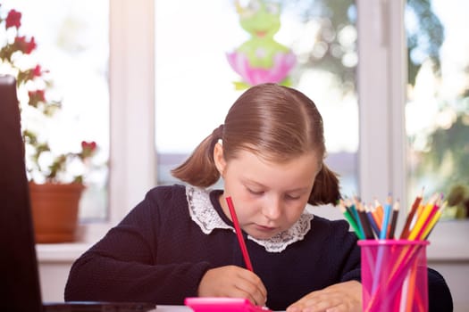 Distance learning-online education. School girl watching online education classes and doing school homework. COVID-19 pandemic forces children online learning.