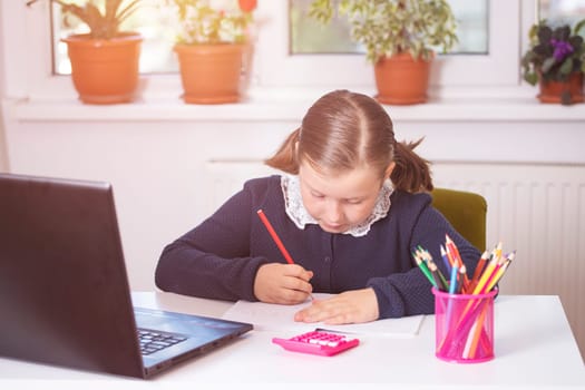 Distance learning-online education. School girl watching online education classes and doing school homework. COVID-19 pandemic forces children online learning.