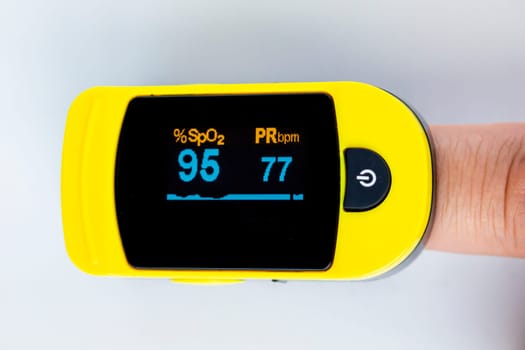 A close up person's finger using a pulse oximetry, noninvasive method for monitoring people's oxygen saturation.
