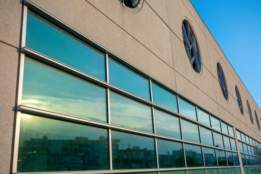 A Tan Building With a Large Window Reflecting the Sunset Sky