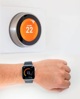 A person checking the room temperature with a smart watch connected to a smart thermostat.
