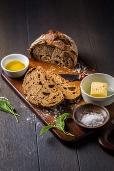 Fresh bread slice with sage butter, olive oil and salt on rustic table on cutting board.