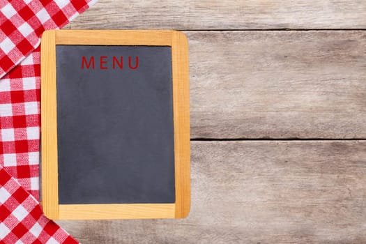 Food recipe template. Empty wooden black board and a red white checkered cloth on rustic bright table. For your food and product display montage. Copy space.